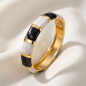 دستبند النگویی پهن مجلسی قفل‌دار با پایه طلایی و قطعات میناکاری شده طرح سنگ مرمر سیاه و سفید