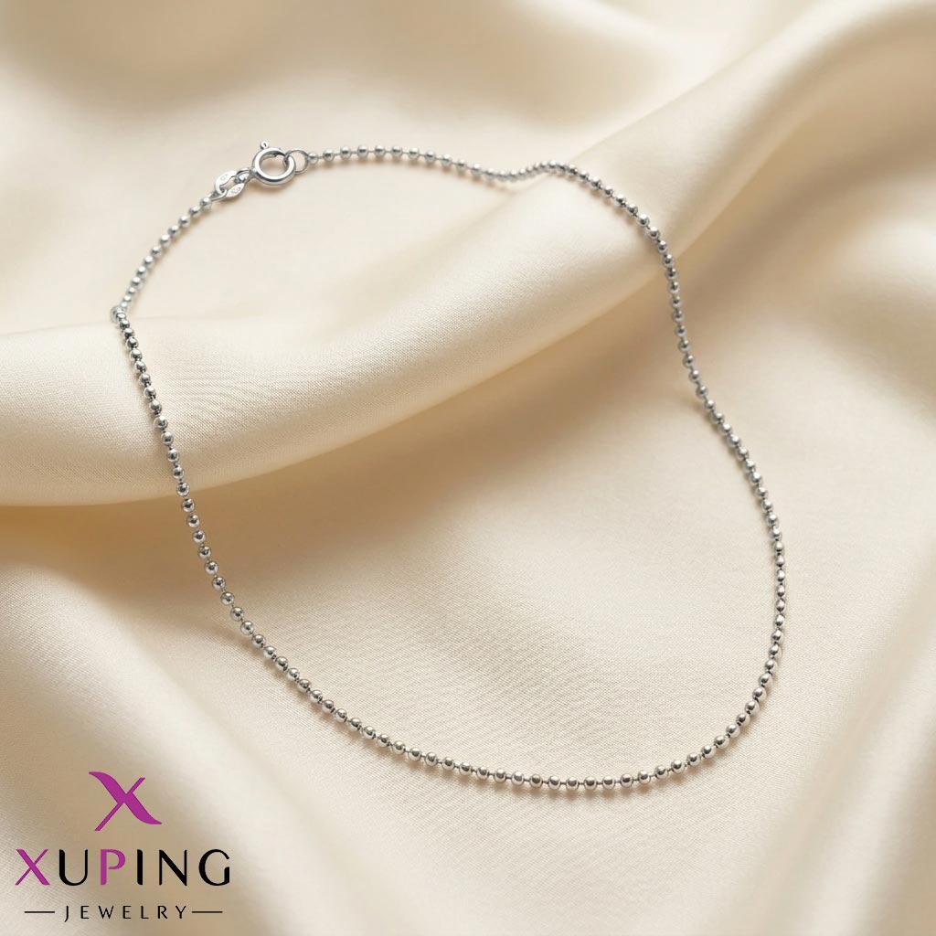 Minimalist-silver-colored-Bead-Necklace زنجیر تک ظریف نقرهای رنگ مدل زنجیر گویدار (ساچمهای) برند ژوپینگ که روی پارچه حریر روشن قرار گرفته است