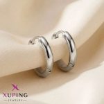 یک جفت گوشواره حلقه‌ای بزرگ ۱.۷ سانتی‌متری، ساده و کلاسیک نقره‌ای رنگ برند ژوپینگ قرار گرفته روی پارچه حریر روشن