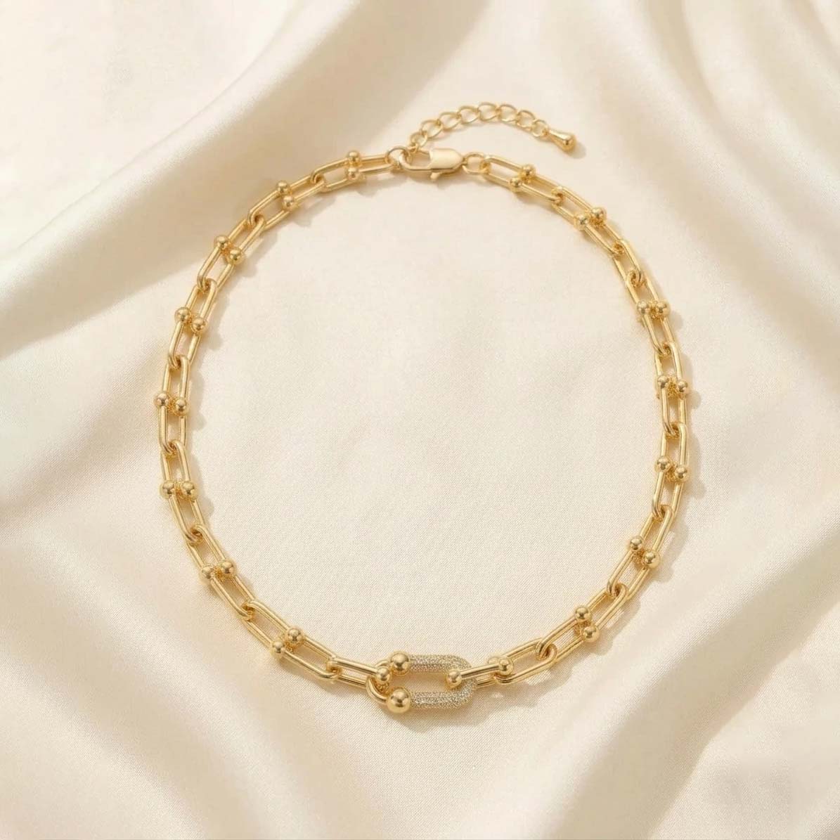 tiffany-style-u-link-pave-Necklace گردنبد طلایی با طرح زنجیر U شکل (مدل تیفانی) و حلقههای مرکزی نگیندار، قرار گرفته روی پارچه حریر روشن